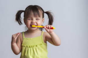 Toddler smiling while brushing her teeth